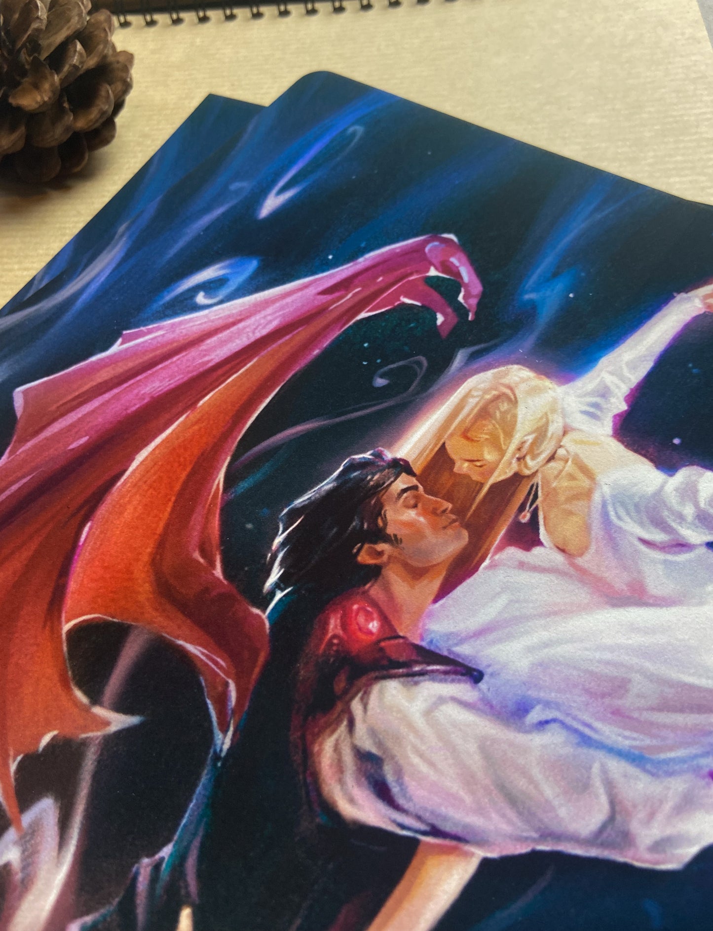 This shows a close up of the faces of Cassian with his large wings and Nesta in her silver dress.